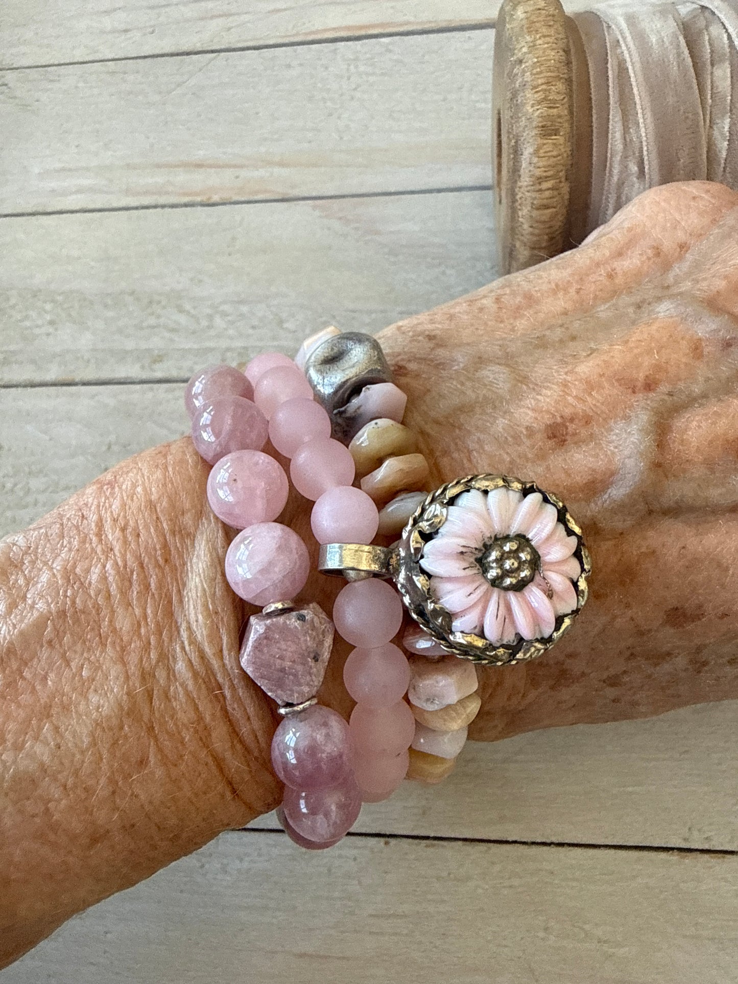 Matte rose quartz beads surround a Tibetan. Peruvian Opal flower charm in this stretch bracelet. 7-7.5”