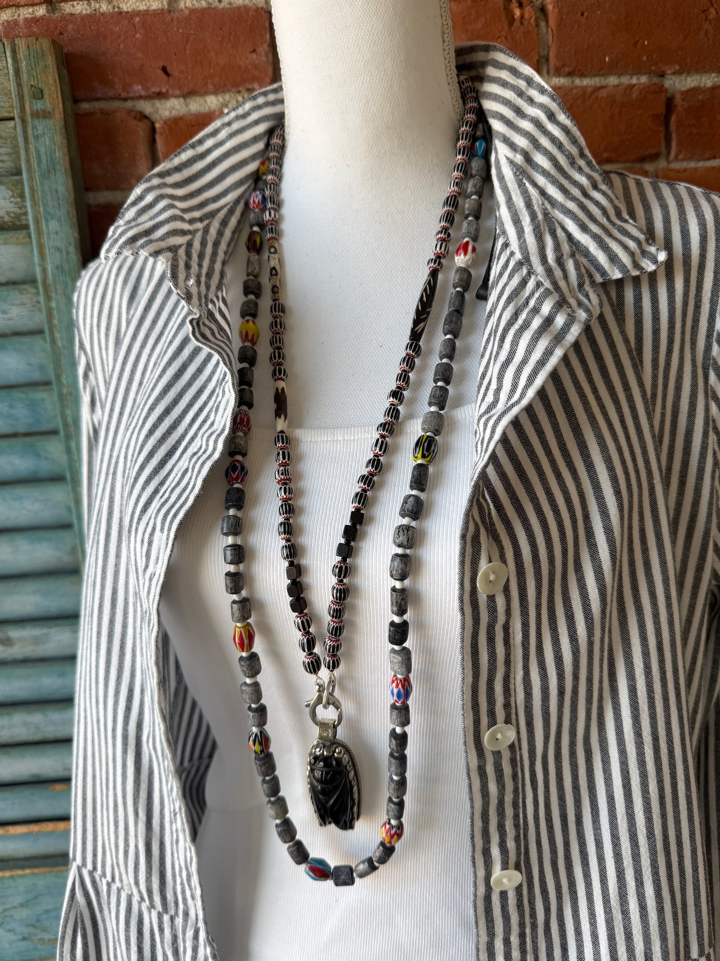 Obsidian beetle pendant on black, red, and white chevron beads with bone accent beads long necklace. Front lobster clasp. 34”