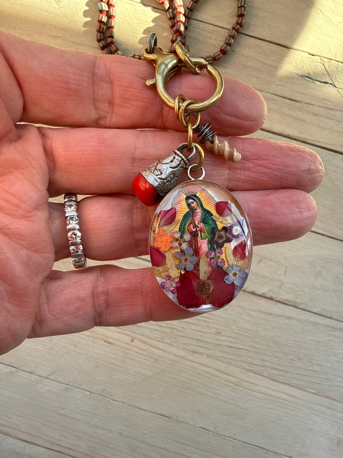 Our Lady. Dried flowers under resin. Handmade with sterling bezel on knotted striped Java beads. 35” necklace.