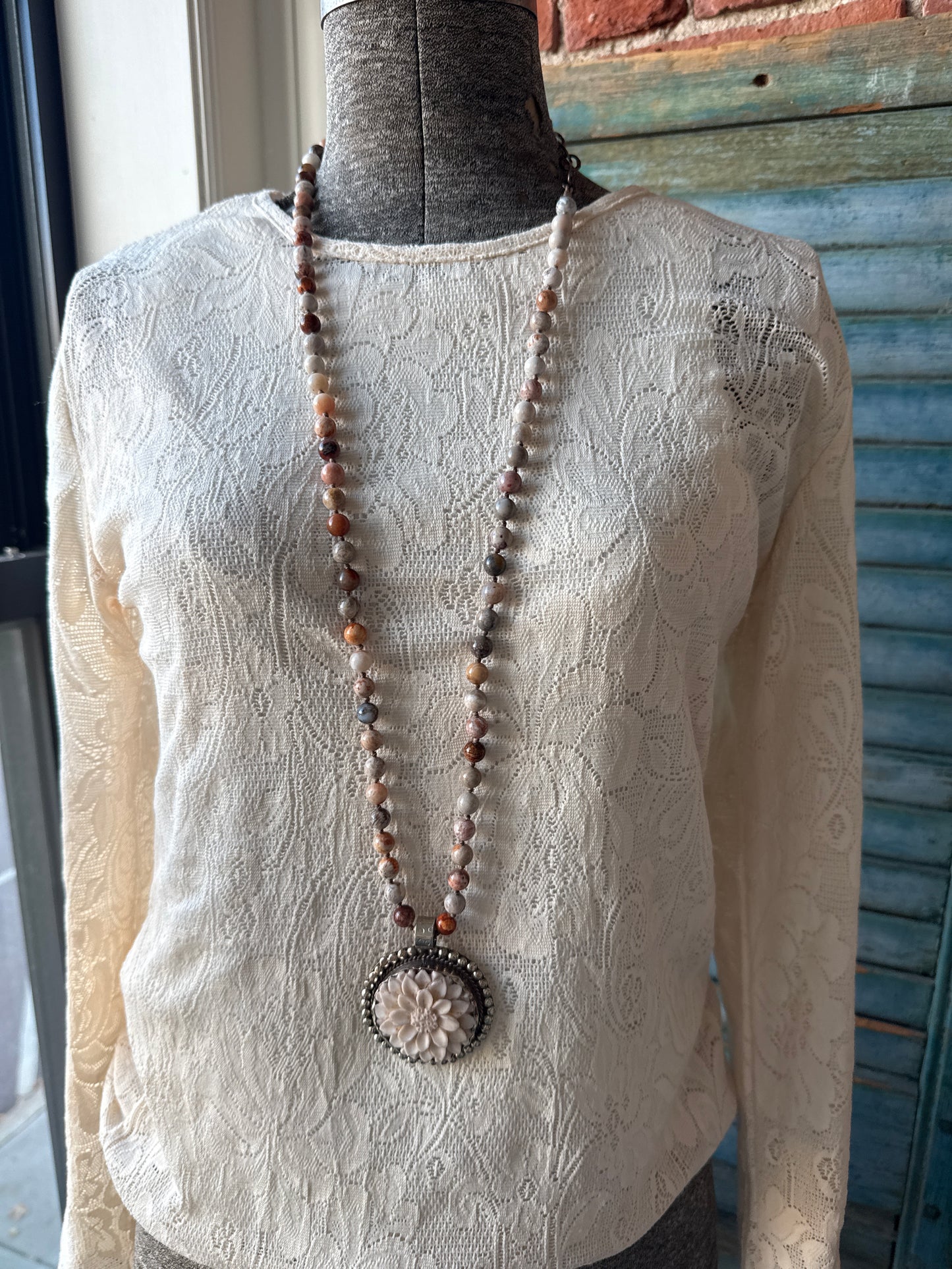 Tibetan carved bone dahlia on knotted fossilized coral long necklace.