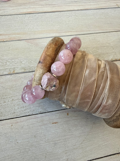 A rough cut, unpolished ruby sits among rose quartz beads in this pink stretch bracelet. 7.5”