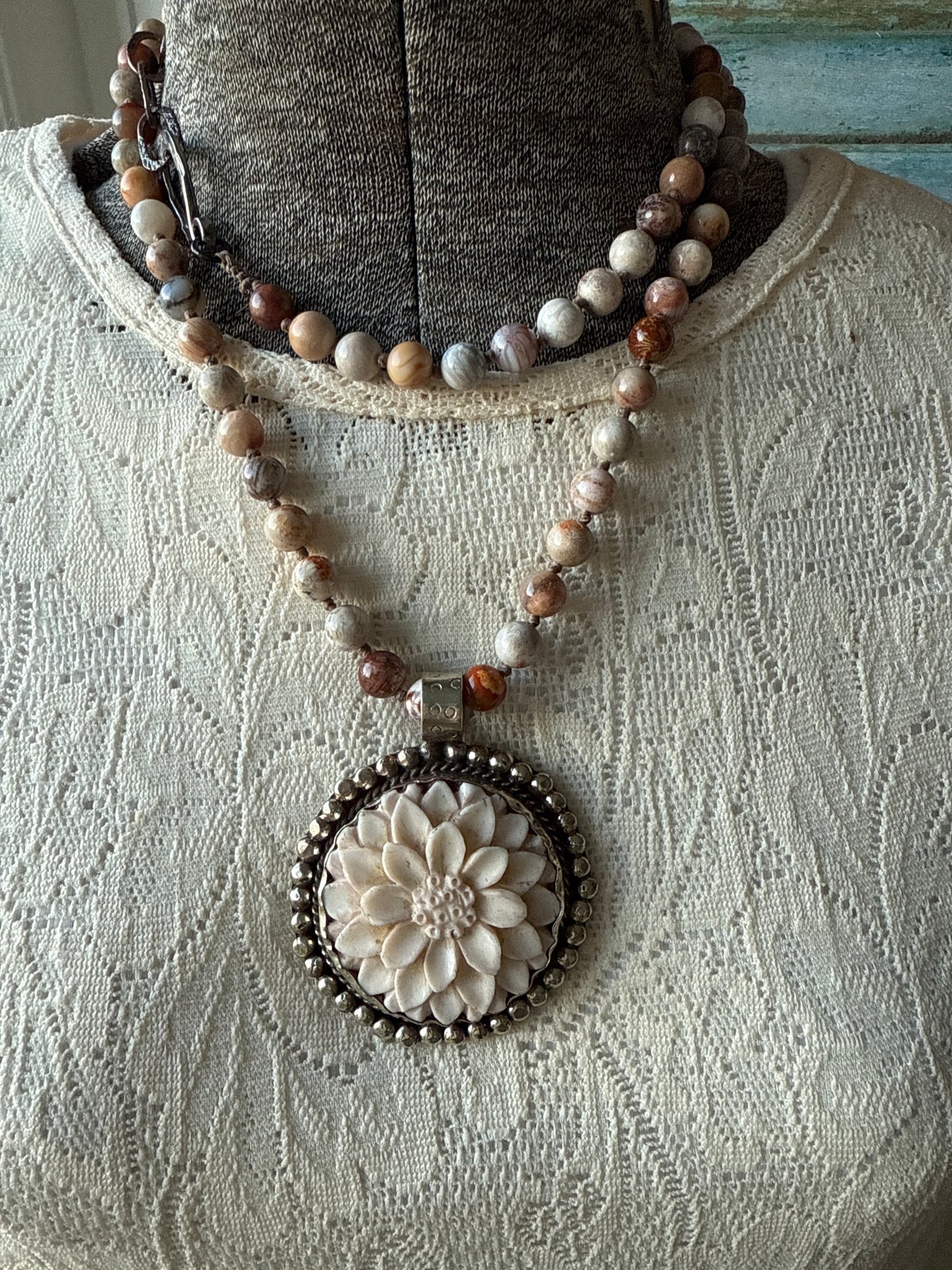 Tibetan carved bone dahlia on knotted fossilized coral long necklace.