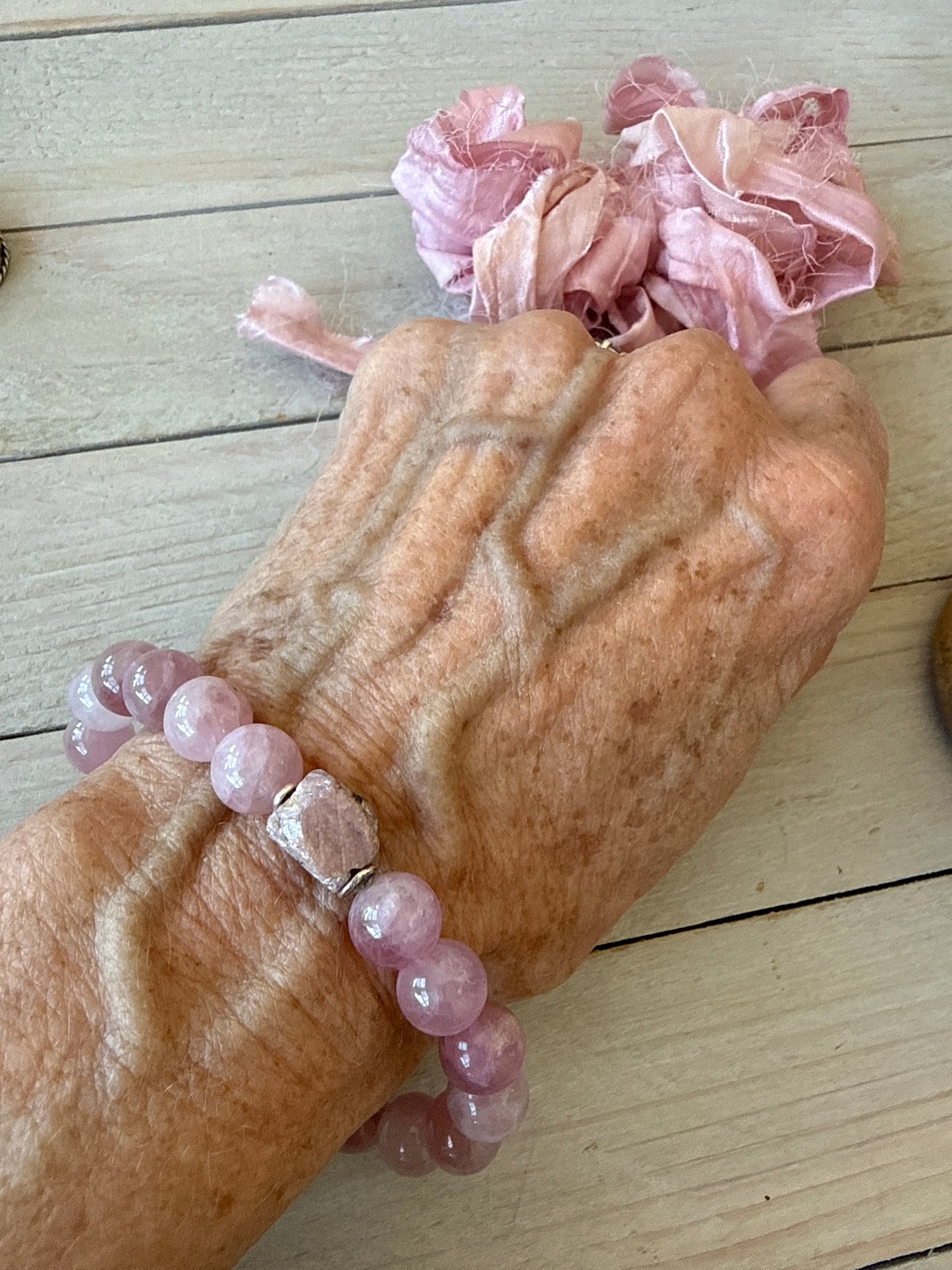 A rough cut, unpolished ruby sits among rose quartz beads in this pink stretch bracelet. 7.5”