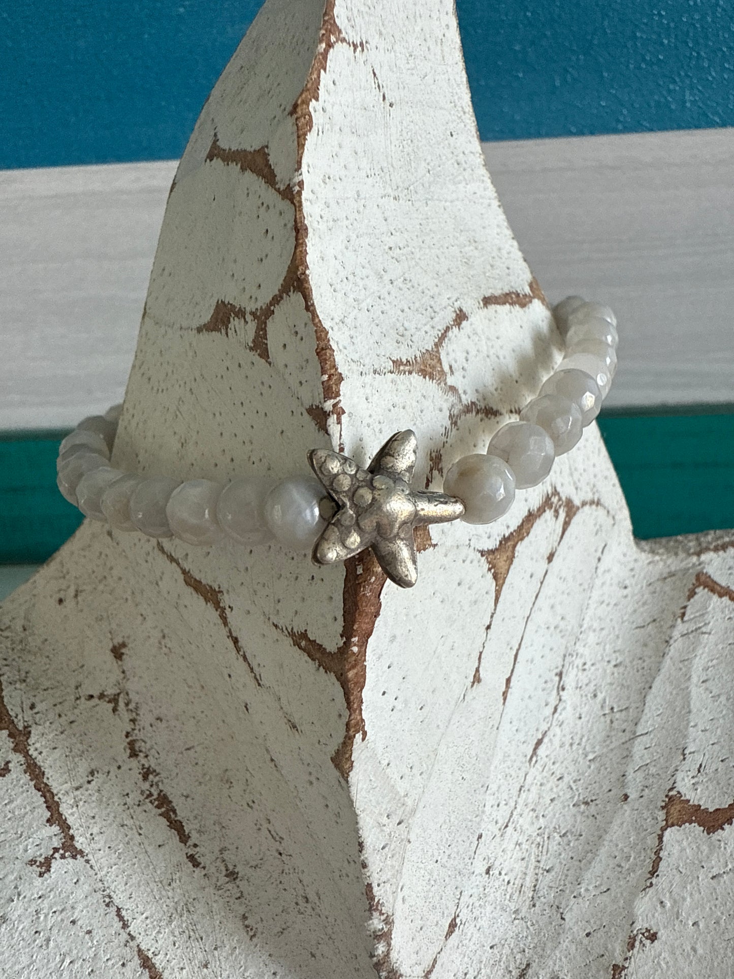 A small, fine silver starfish adorns this faceted moonstone bracelet. 7-7.5” stretch.