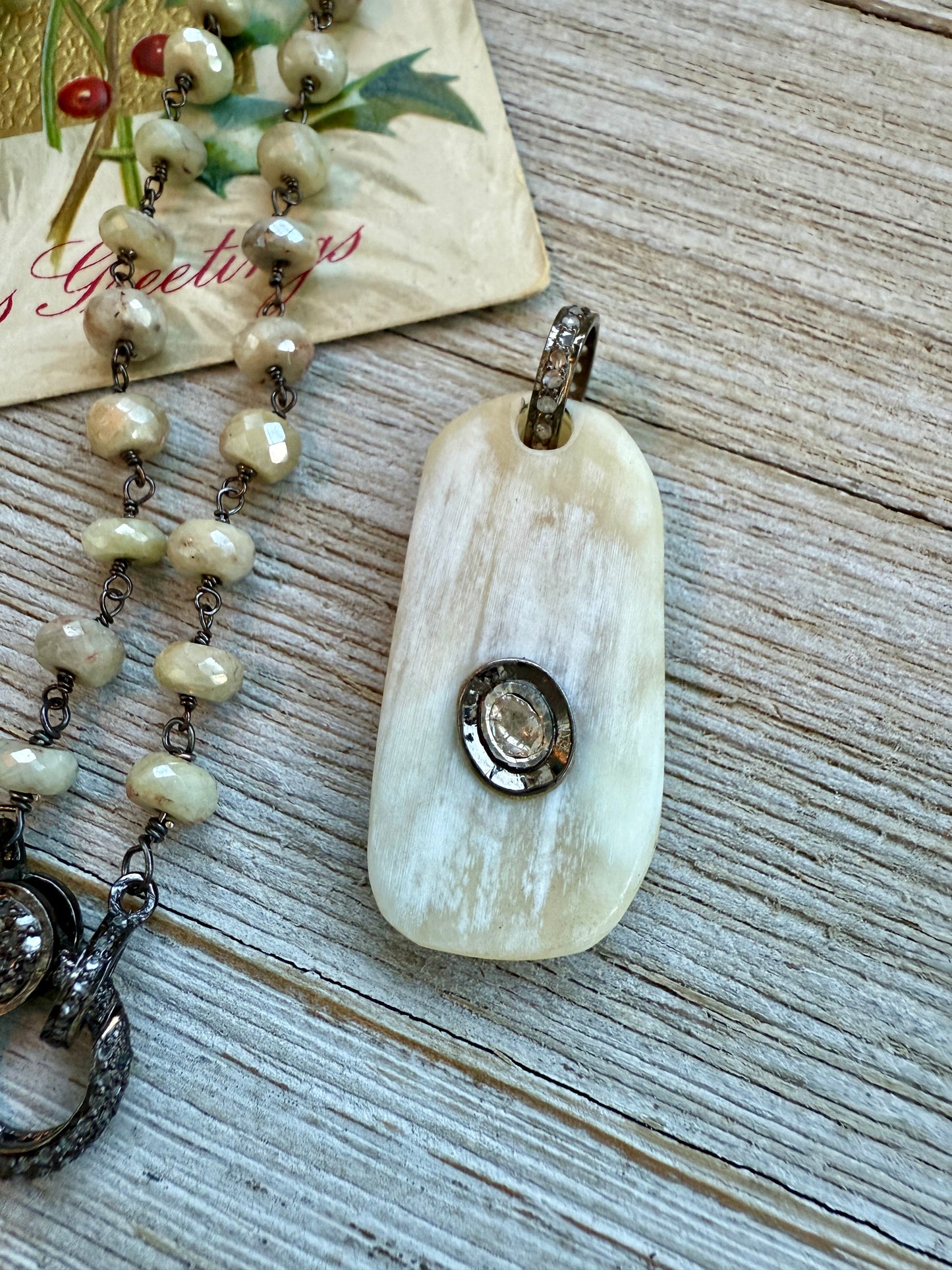 Cream colored bone pendant with inlayed Polki diamond; diamond bale and clasp, cream silverite chain necklace. 31.5” chain.