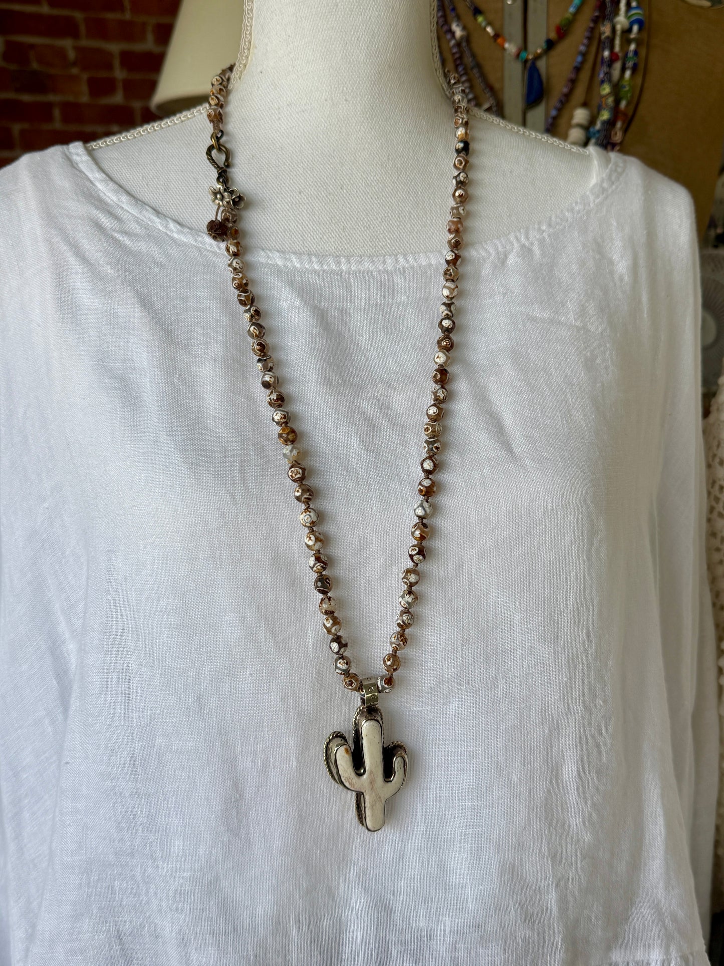 Bone cactus pendant on Dzi agates with fine silver embellishments. 34.5”