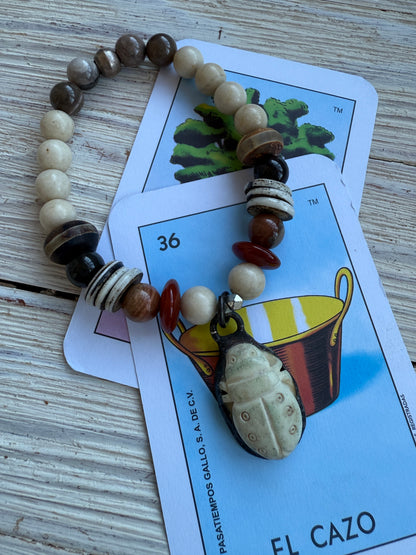 A bone scarab dangles from a mix of earthy beads stretch bracelet 6.5-7”