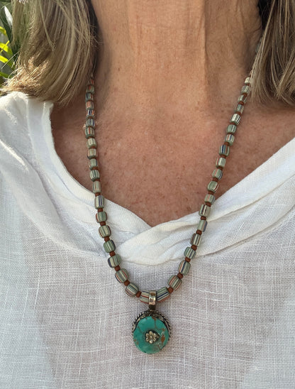 Tibetan turquoise pendant on striped Java beads. Fine silver hook clasp. 21”.
