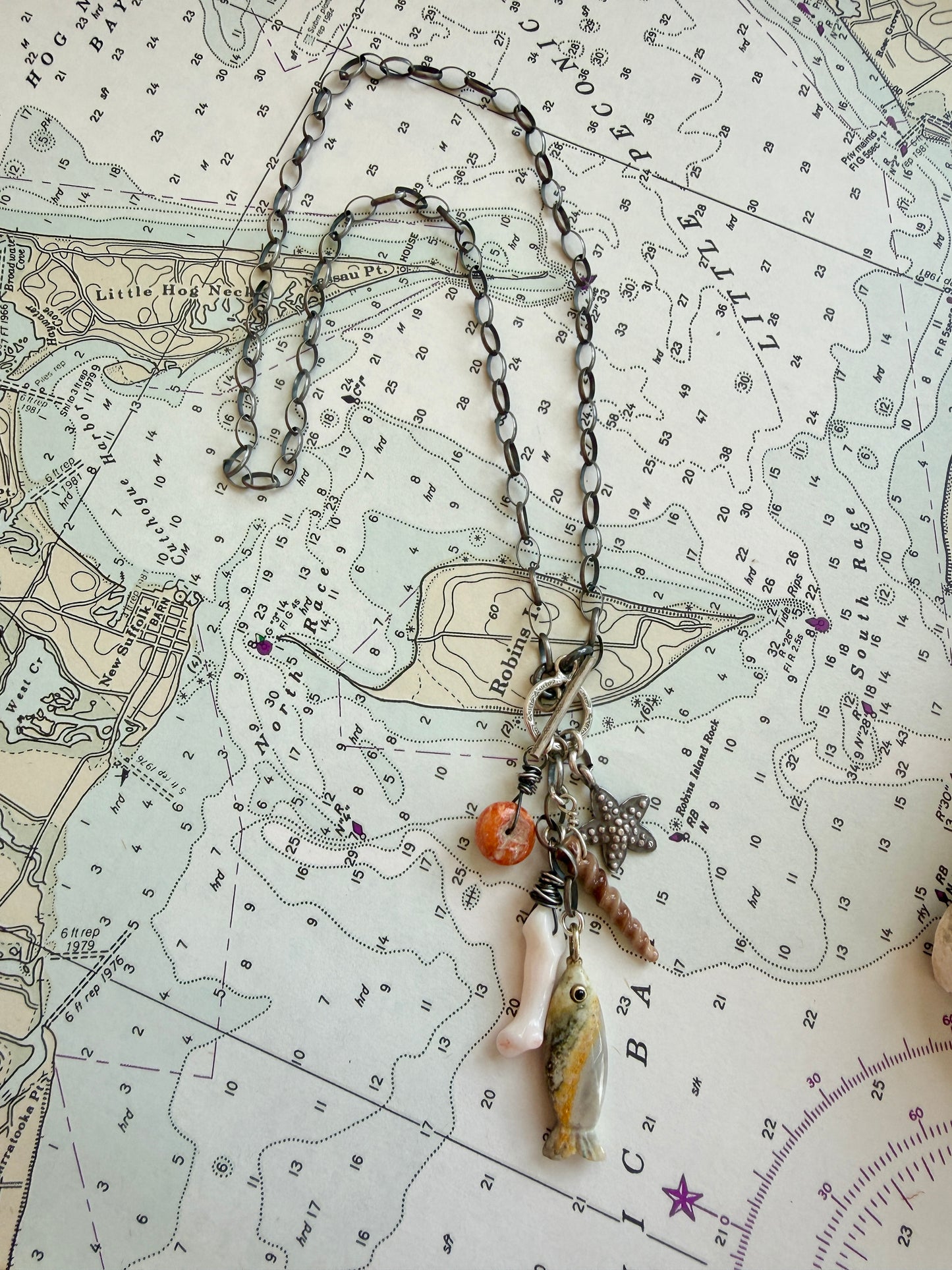 Oxidized sterling chain necklace with front toggle, bumblebee jasper fish, fine silver starfish, white coral, shell, and spiny oyster danglies.
