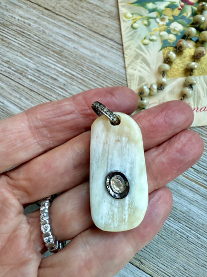 Cream colored bone pendant with inlayed Polki diamond; diamond bale and clasp, cream silverite chain necklace. 31.5” chain.