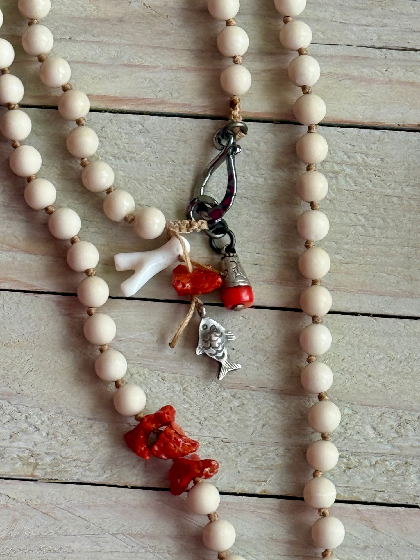 Tibetan carved bone fish on knotted riverstone and coral long necklace. Coral and fine silver fish charms.
