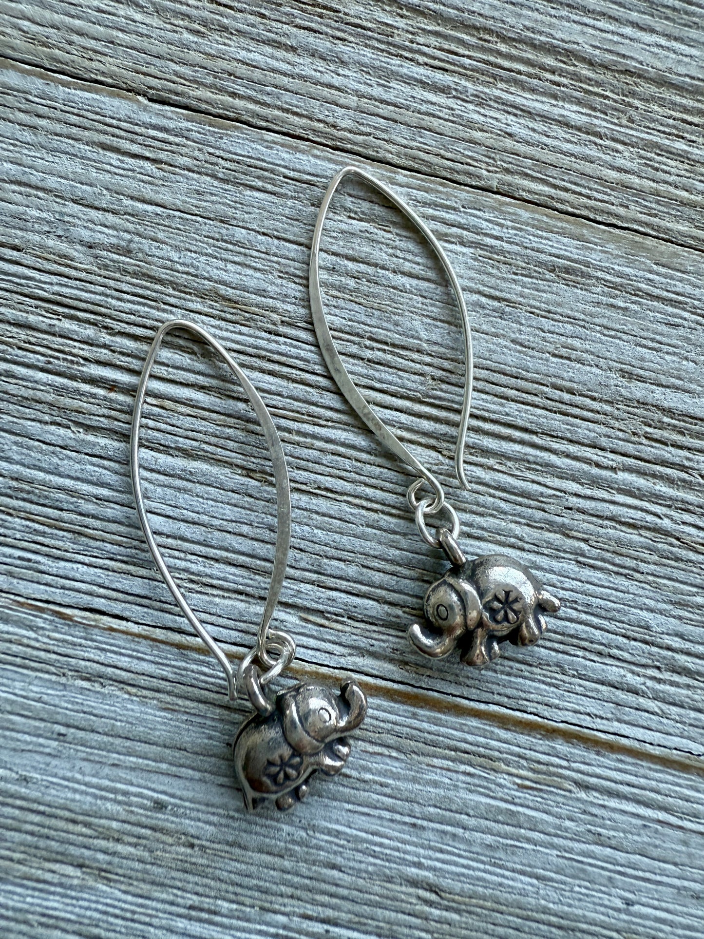 Fine silver elephant earrings on elliptical sterling ear wires.