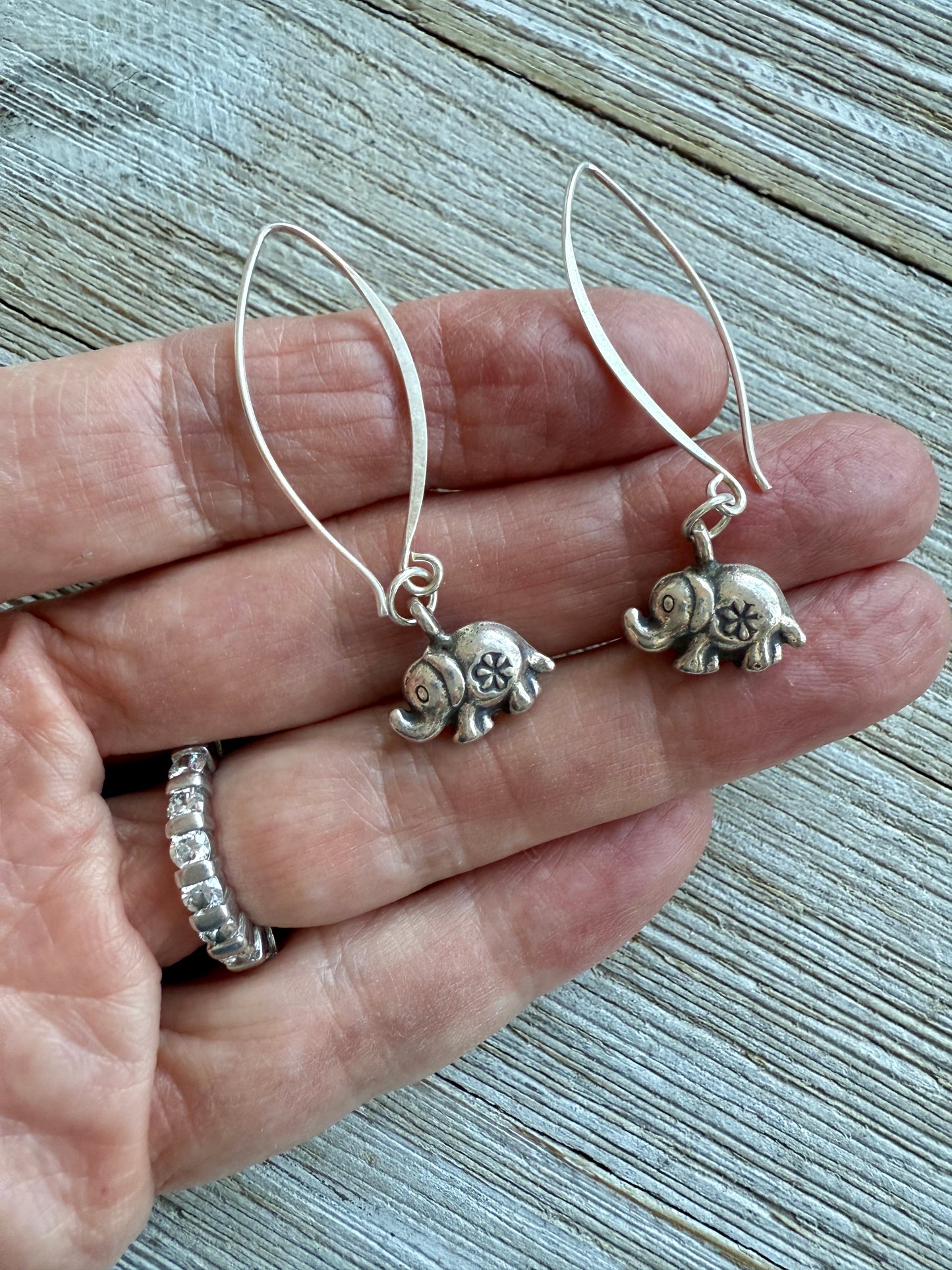 Fine silver elephant earrings on elliptical sterling ear wires.