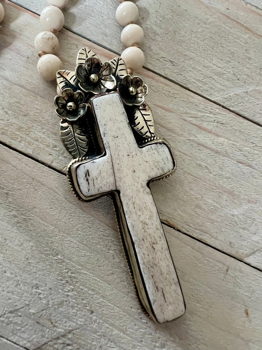 Bone cross with floral accents on creamy riverstone beads. Hand knotted long necklace.