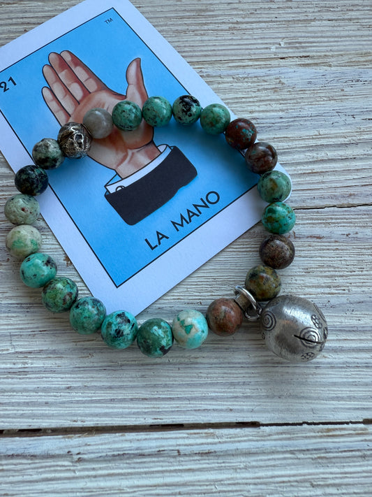 Turquoise beads surround a Karen Hill Tribe bell bead made of fine silver for this stretch bracelet. 6-5-7”.