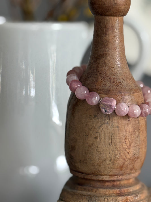A rough cut, unpolished ruby sits among rose quartz beads in this pink stretch bracelet. 7.5”