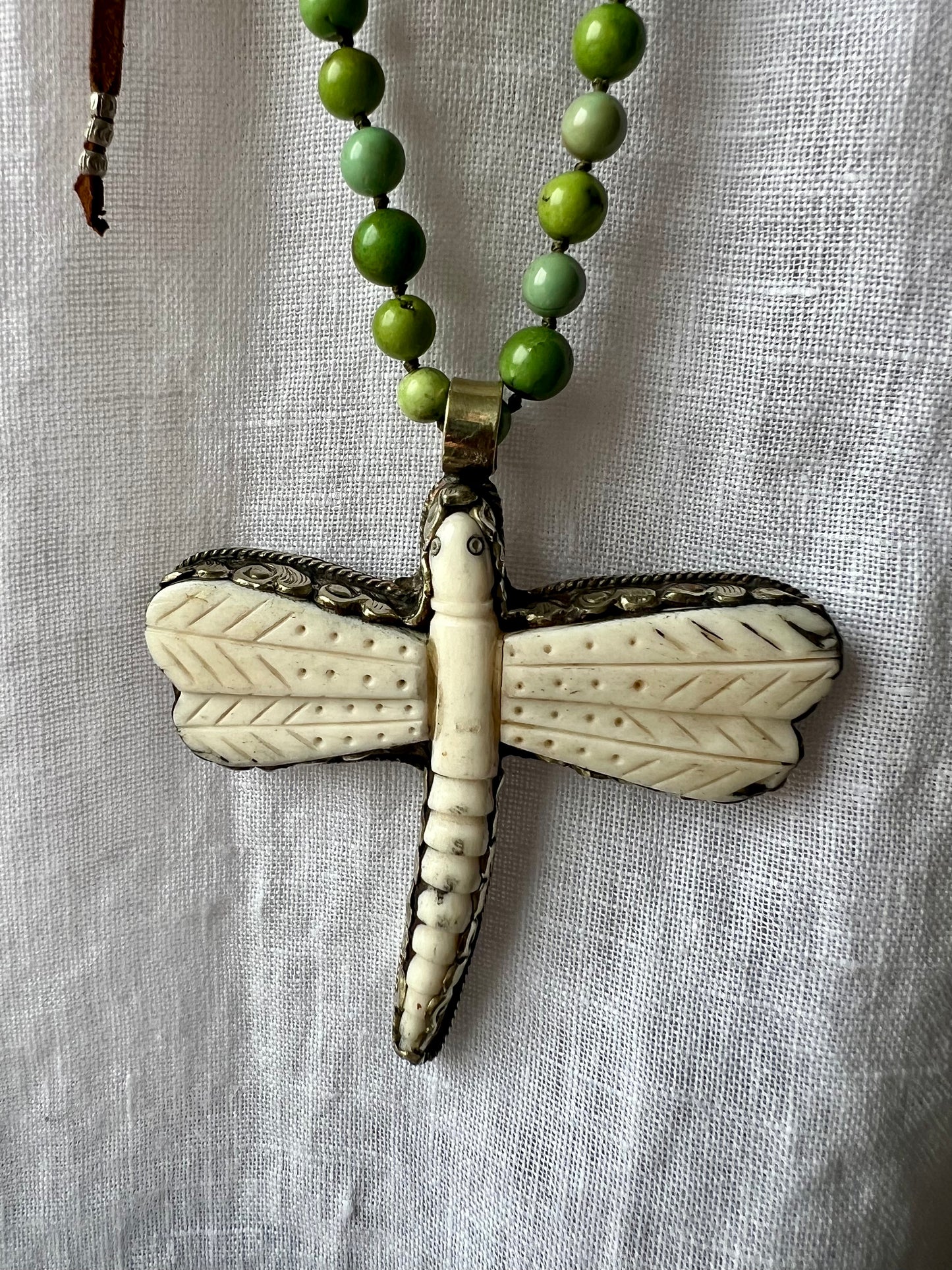 Tibetan carved bone dragonfly pendant on green and blue turquoise. Long, knotted necklace.