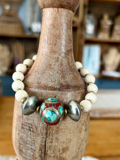 Tibetan inlay bead with coral and turquoise on matte riverstone beads. Stack stretch bracelet.