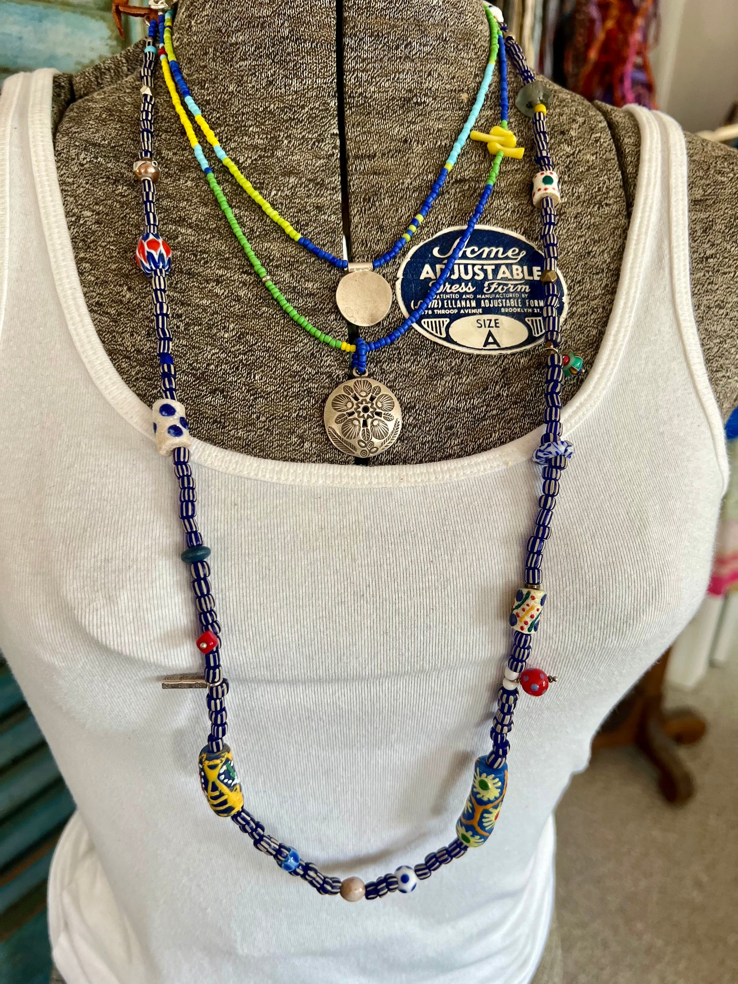 Blue, turquoise, green, and yellow glass beads from Java with a full moon pendant of fine silver.