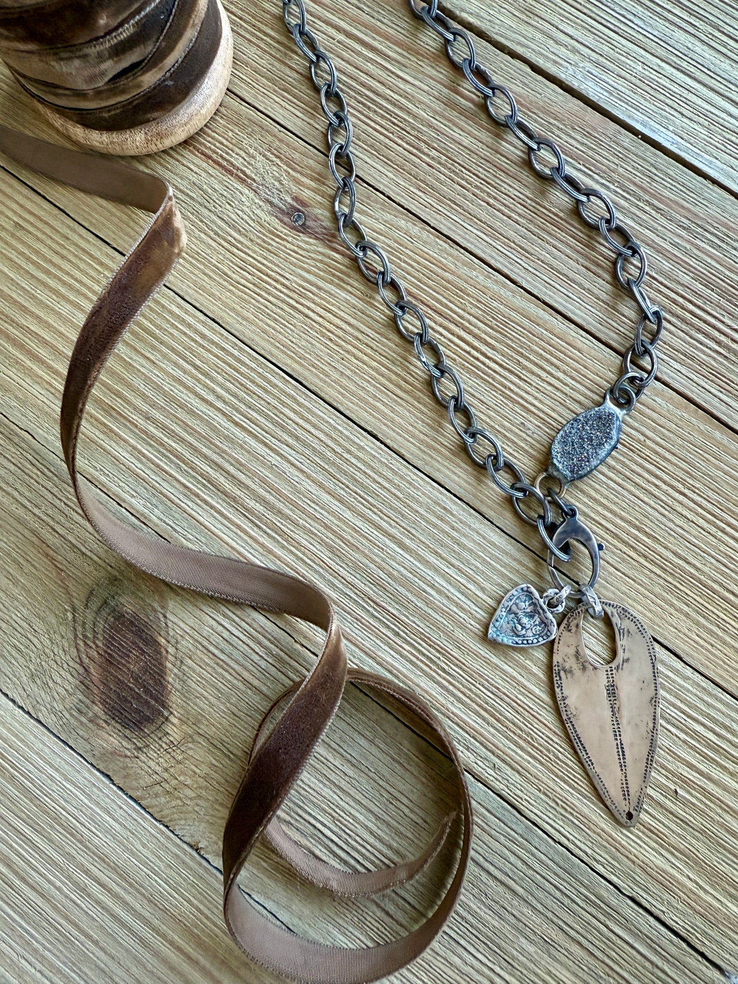 A rustic bronze shield hangs from an oxidized sterling chain. A sterling heart and pyrite add interest. Oxidized sterling lobster clasp allows you to change pendants out and adjust length. 19”