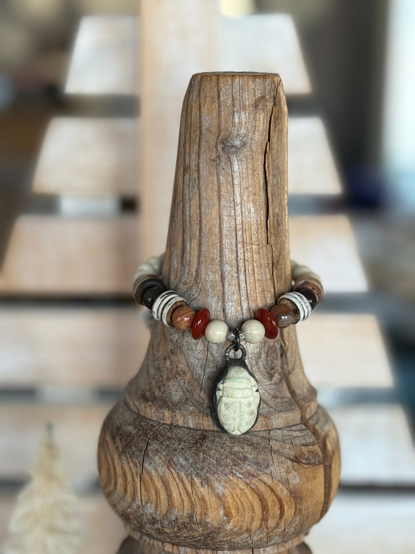 A bone scarab dangles from a mix of earthy beads stretch bracelet 6.5-7”