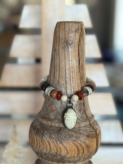A bone scarab dangles from a mix of earthy beads stretch bracelet 6.5-7”
