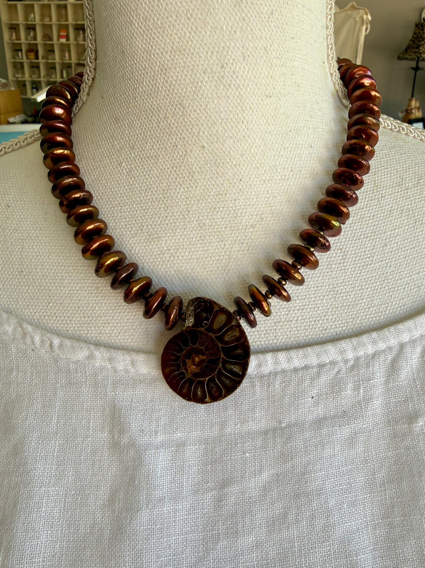 A natural ammonite fossil and chocolate brown button pearl necklace.
