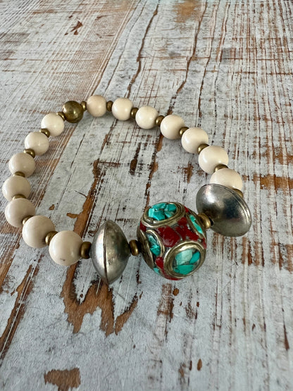 Tibetan inlay bead with coral and turquoise on matte riverstone beads. Stack stretch bracelet.