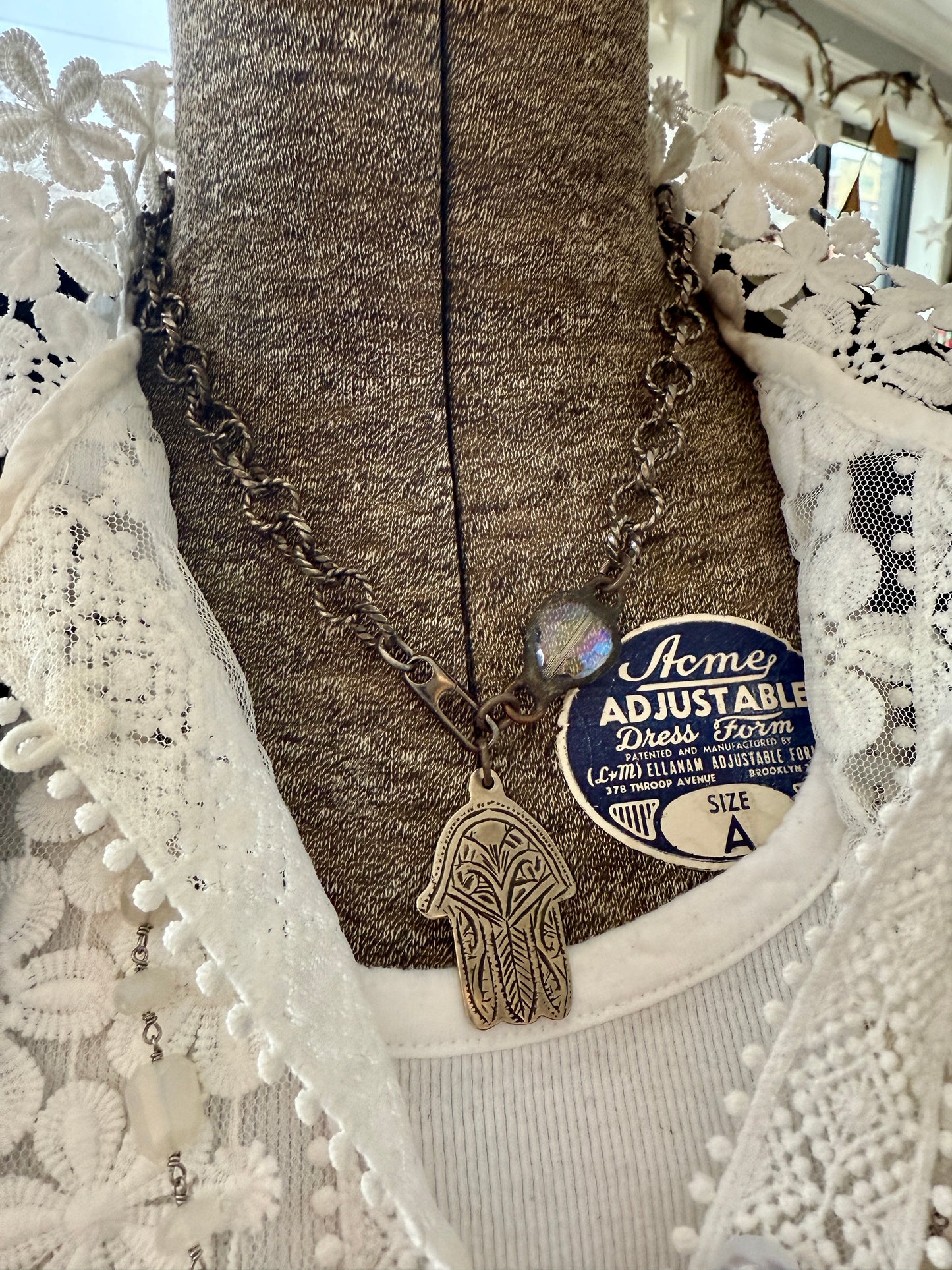 Chunky oxidized sterling rope chain with a crystal hear, sterling carabiner clasp, and stamped bronze hamsa pendant. 18”