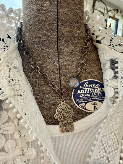 Chunky oxidized sterling rope chain with a crystal hear, sterling carabiner clasp, and stamped bronze hamsa pendant. 18”