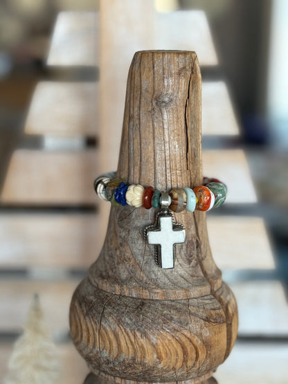 A bone cross adorns this beaded stretch bracelet. 7”