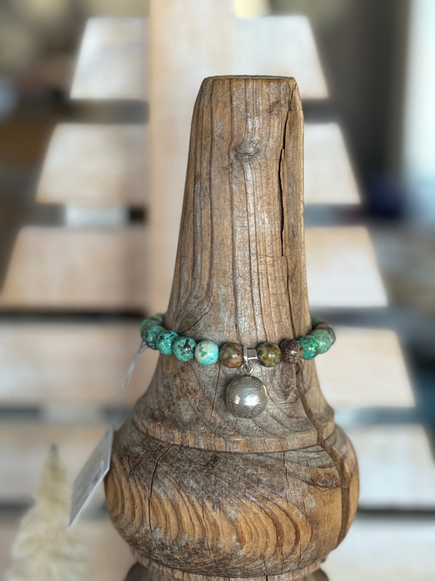 Turquoise beads surround a Karen Hill Tribe bell bead made of fine silver for this stretch bracelet. 6-5-7”.