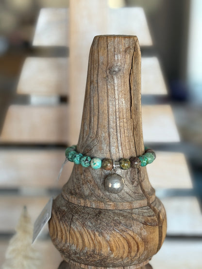 Turquoise beads surround a Karen Hill Tribe bell bead made of fine silver for this stretch bracelet. 6-5-7”.