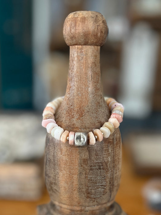 Heishi cut pink opals surround a fine silver pinched cube. Fine silver spacers. 6” stretch stack bracelet.