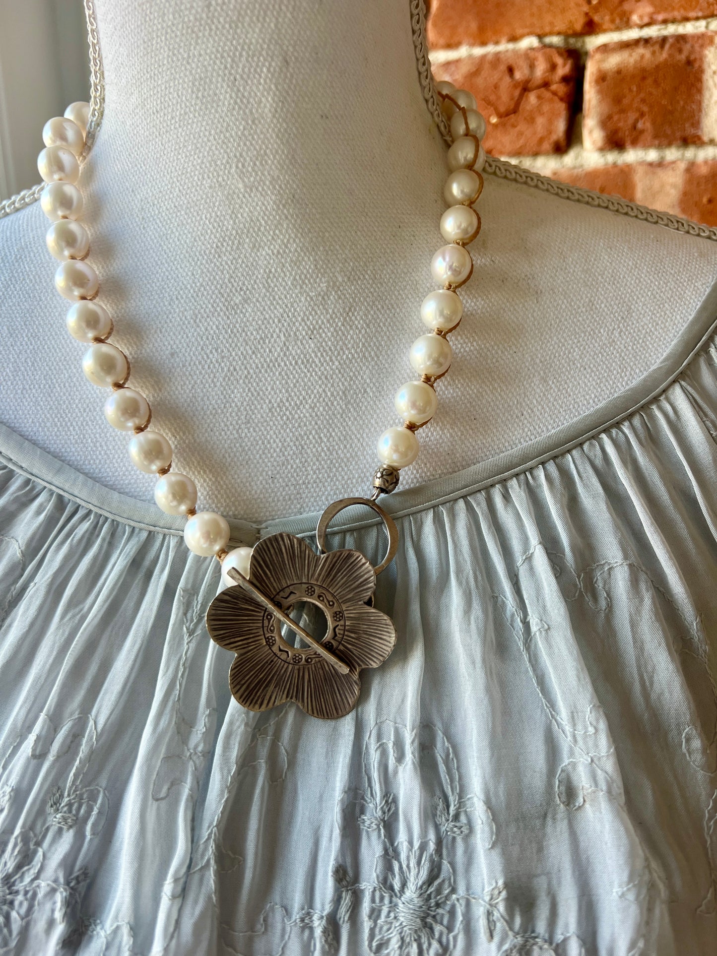 Fine silver flower on hand knotted pearls necklace. Front or side toggle