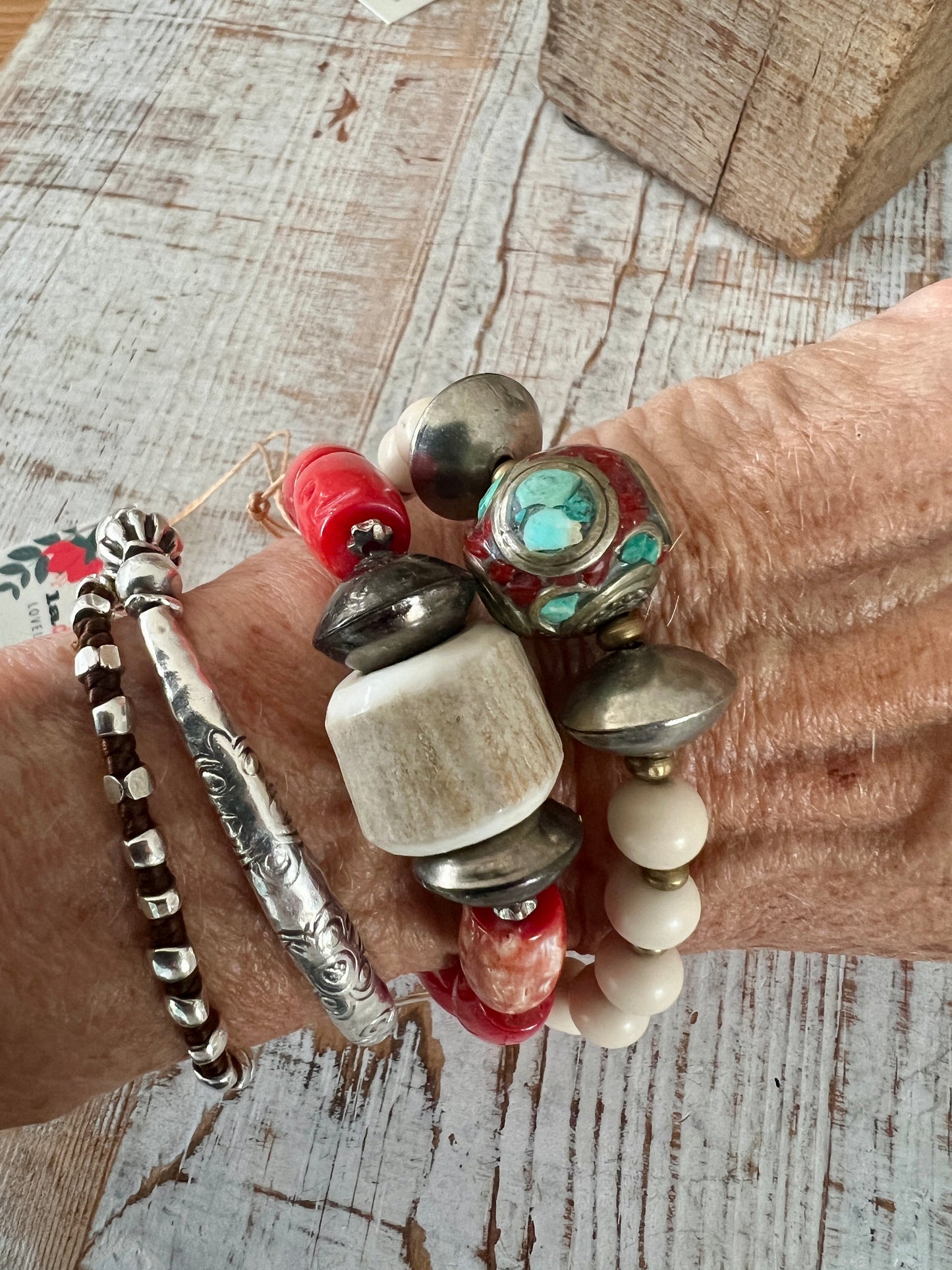 Tibetan inlay bead with coral and turquoise on matte riverstone beads. Stack stretch bracelet.