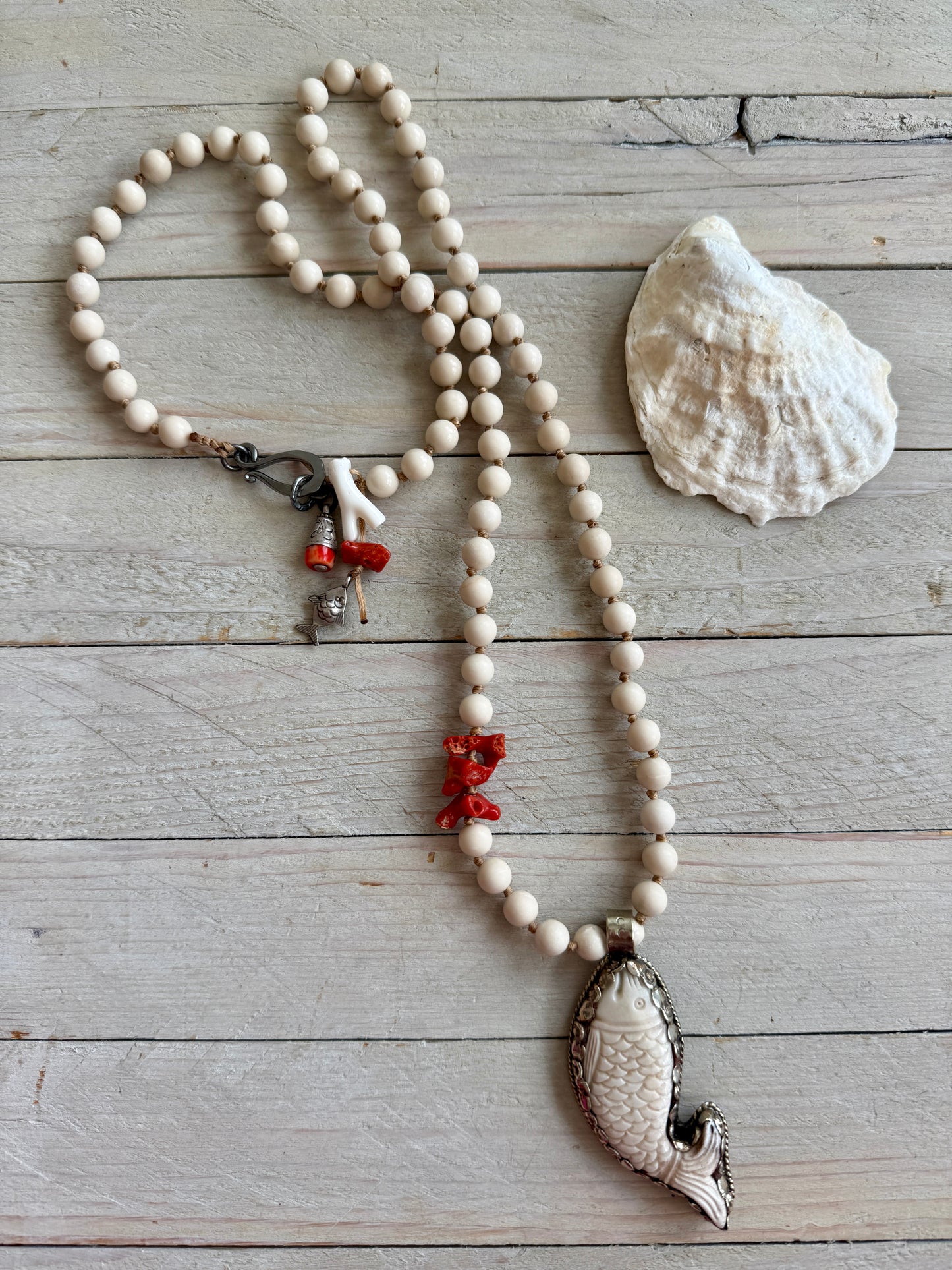 Tibetan carved bone fish on knotted riverstone and coral long necklace. Coral and fine silver fish charms.