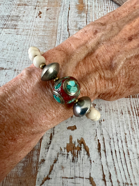 Tibetan inlay bead with coral and turquoise on matte riverstone beads. Stack stretch bracelet. 7”