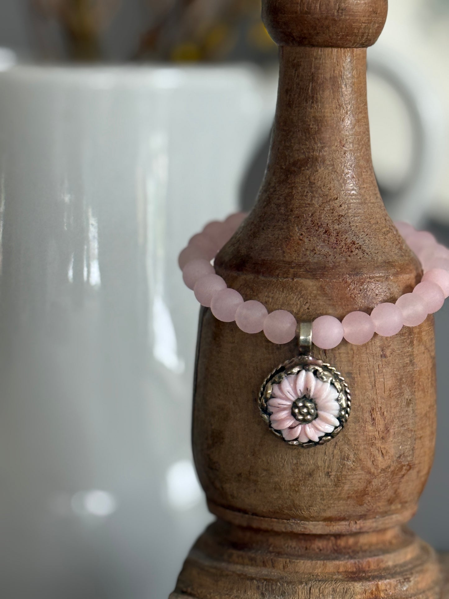 Matte rose quartz beads surround a Tibetan. Peruvian Opal flower charm in this stretch bracelet. 7-7.5”