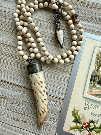 Carved bone on cream riverstone, smoky quartz accents long necklace. 36”