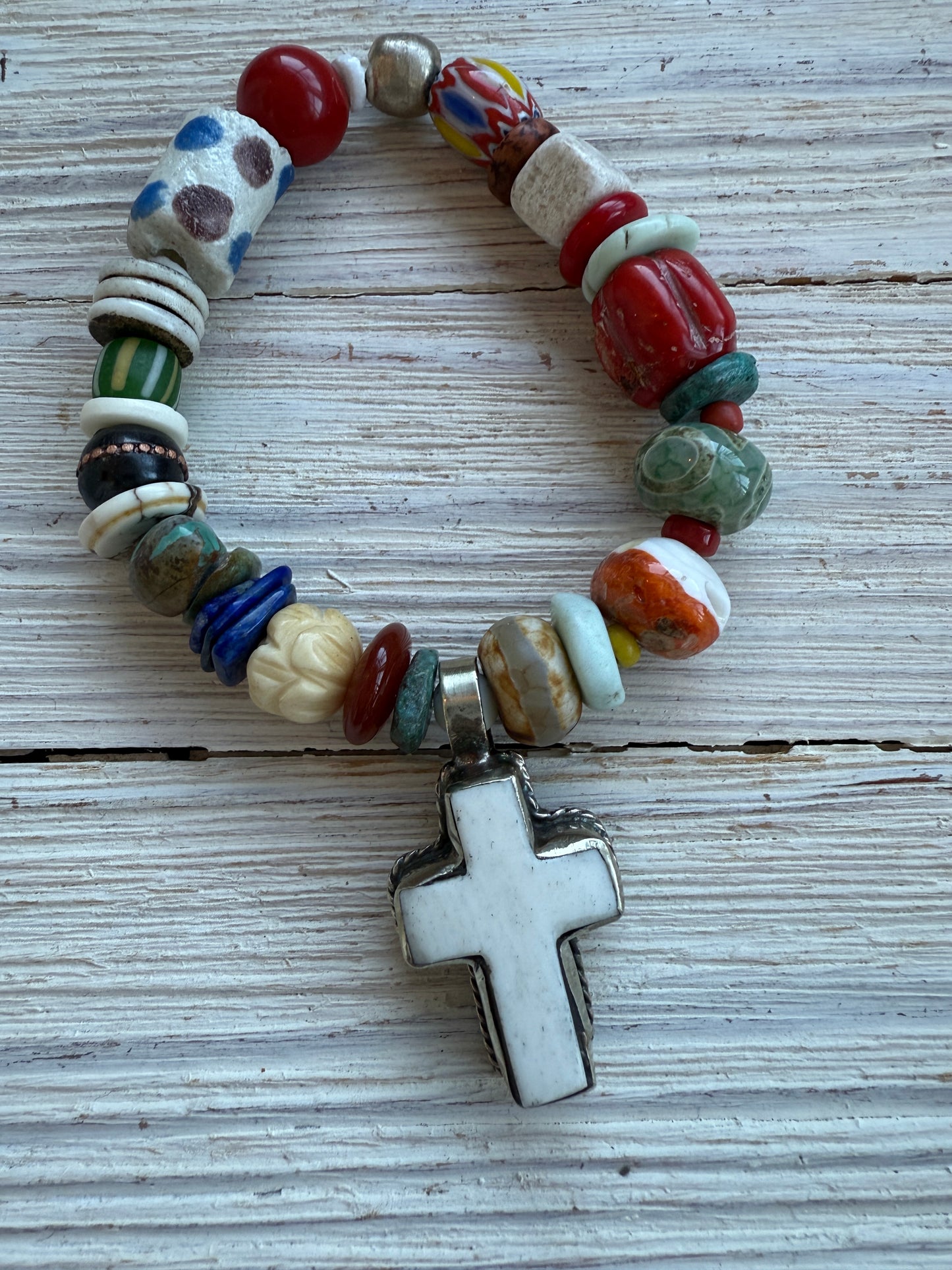 A bone cross adorns this beaded stretch bracelet. 7”