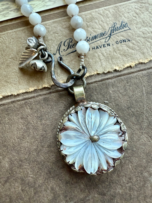 Tibetan mother of pearl daisy pendant with repousé back on faceted white agates. Front hook closure. 23”.