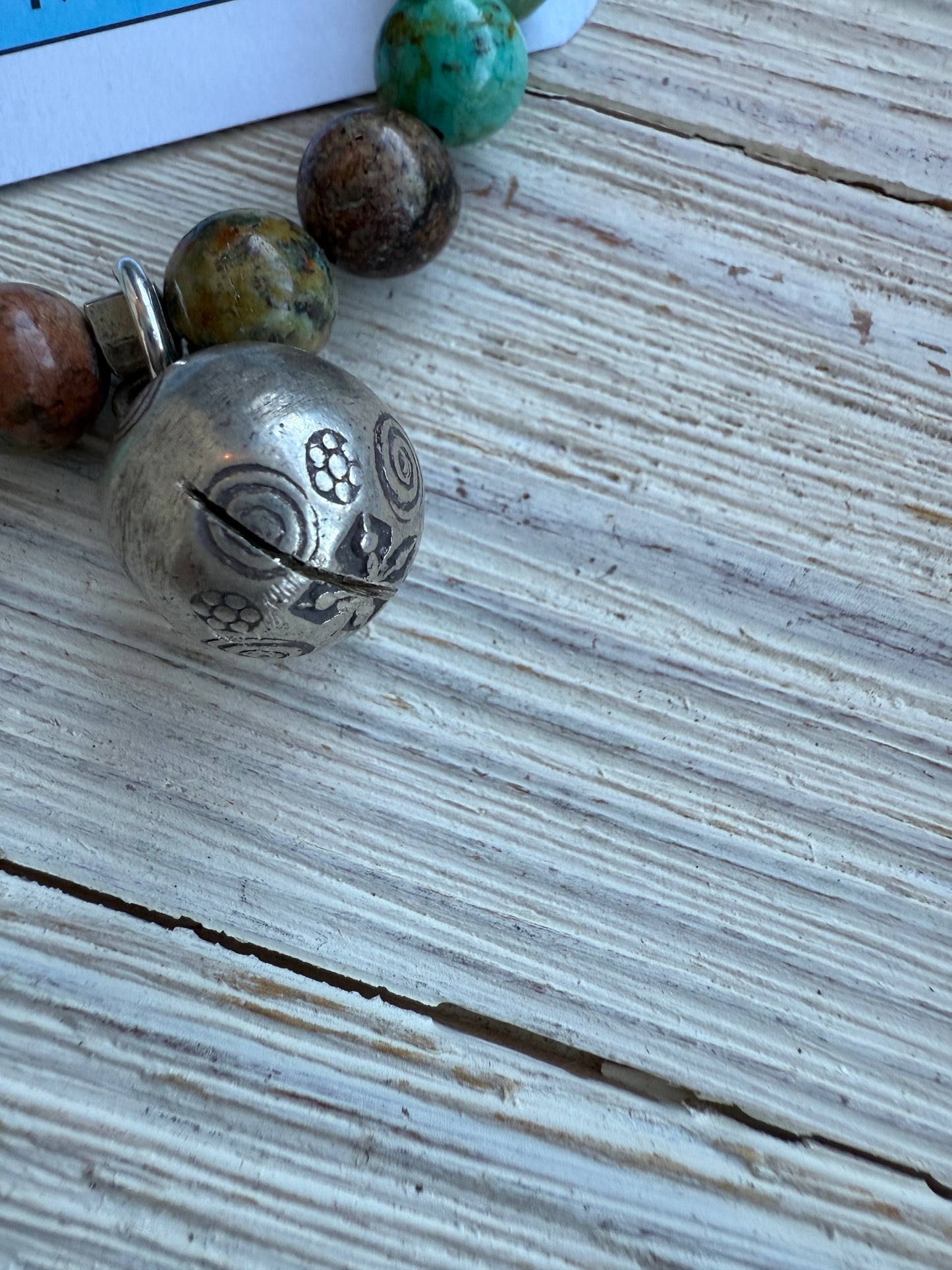 Turquoise beads surround a Karen Hill Tribe bell bead made of fine silver for this stretch bracelet. 6-5-7”.