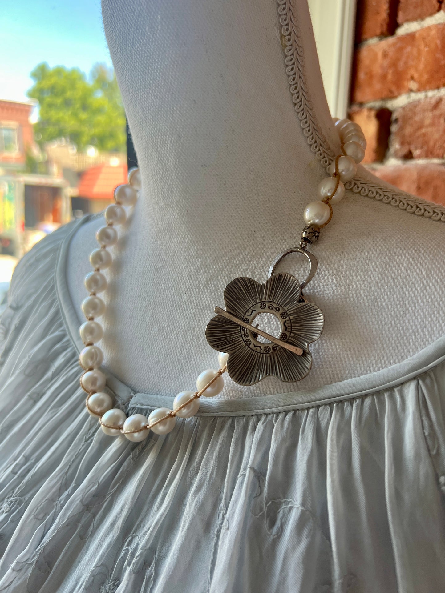 Fine silver flower on hand knotted pearls necklace. Front or side toggle