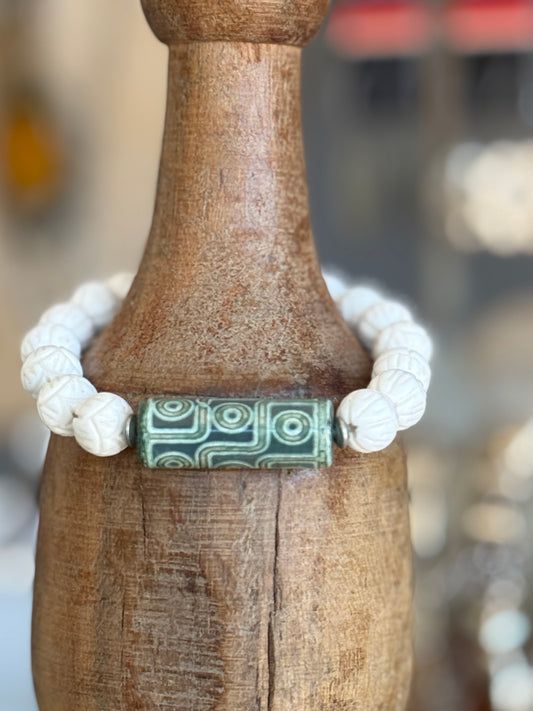 Carved white coral beads with a green Dzi agate focal bead stretch bracelet. 7”.