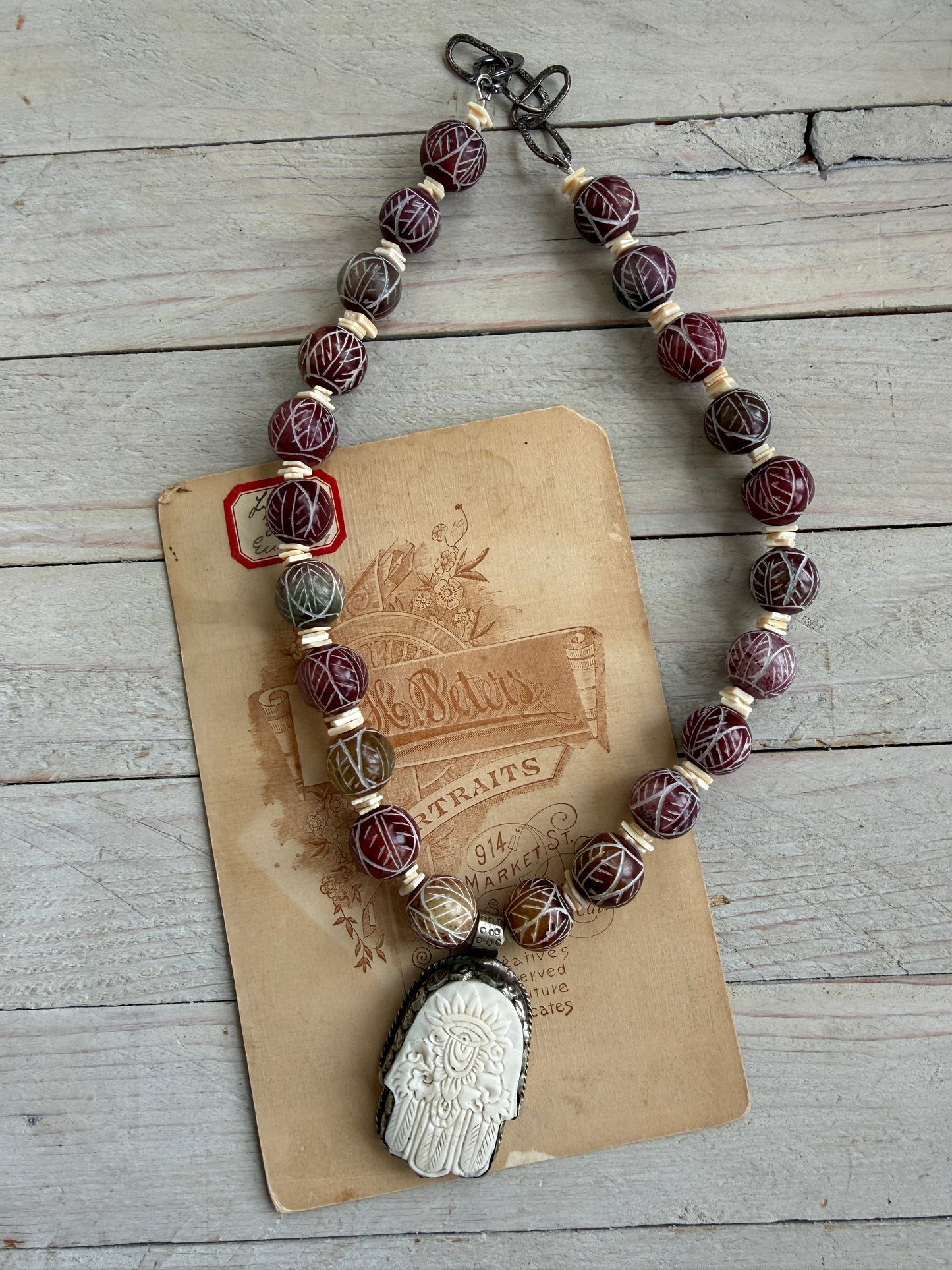 Carved red jade with carved bone hamsa short necklace.