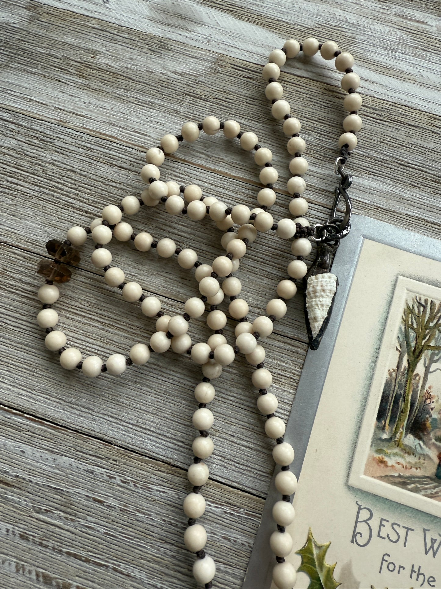 Carved bone on cream riverstone, smoky quartz accents long necklace. 36”