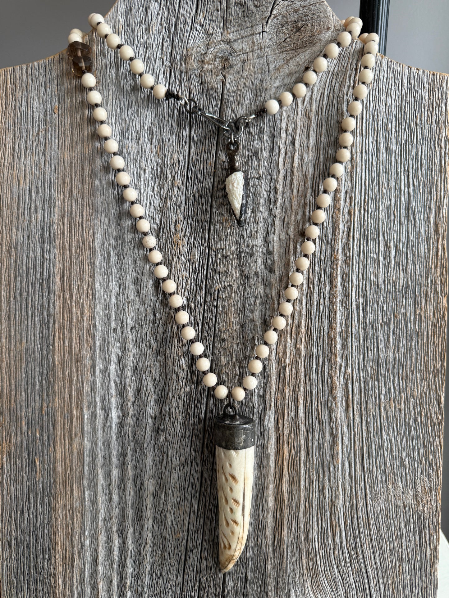 Carved bone on cream riverstone, smoky quartz accents long necklace. 36”