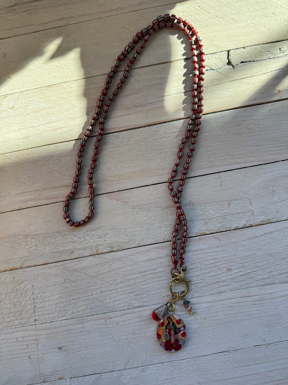 Our Lady. Dried flowers under resin. Handmade with sterling bezel on knotted striped Java beads. 35” necklace.
