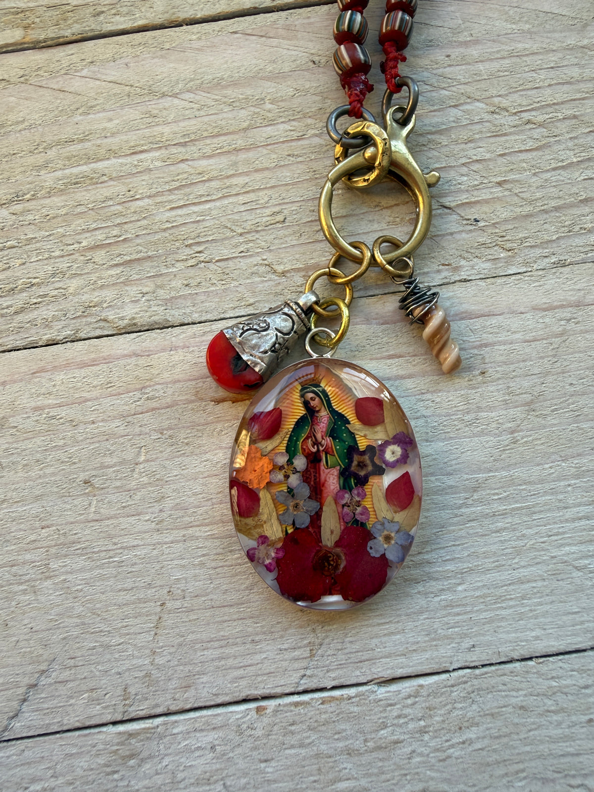 Our Lady. Dried flowers under resin. Handmade with sterling bezel on knotted striped Java beads. 35” necklace.